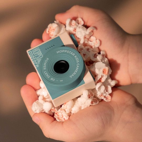 Mały niebieski aparat fotograficzny dla dzieci trzymany w dłoniach z popcornem. Hoppstar Aparat fotograficzny dla dzieci Popcorn Bay