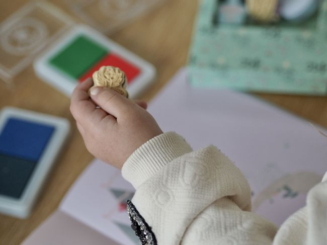 Dziecięca ręka trzymająca stempel z motywem baletnicy obok kolorowych poduszek z tuszem do stempelków. Floss&Rock Baletnice Zestaw Kolorowych Pieczątek i Książeczka
