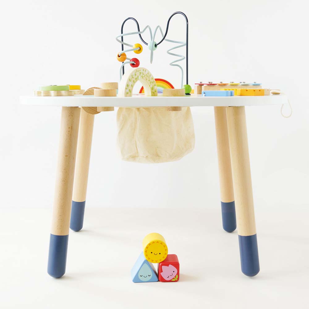Drewniany stolik edukacyjny z kolorowymi elementami do zabawy dla dziecka z nogami w dwóch odcieniach beżu i niebieskiego oraz wiszącą torbą na zabawki. Le Toy Van Stolik edukacyjny