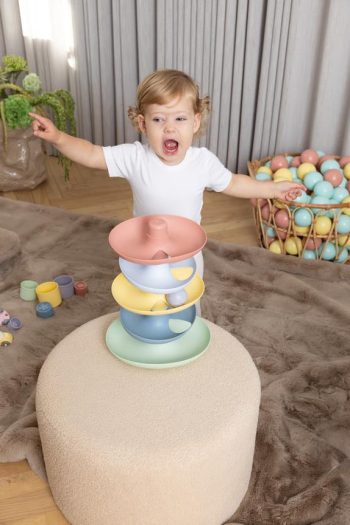 Dziecko bawiące się pastelowym kulodromem z trzema poziomami dla niemowląt i małych dzieci. Dantoy Tor kulkowy kulodrom dla dzieci 10 m-cy+
