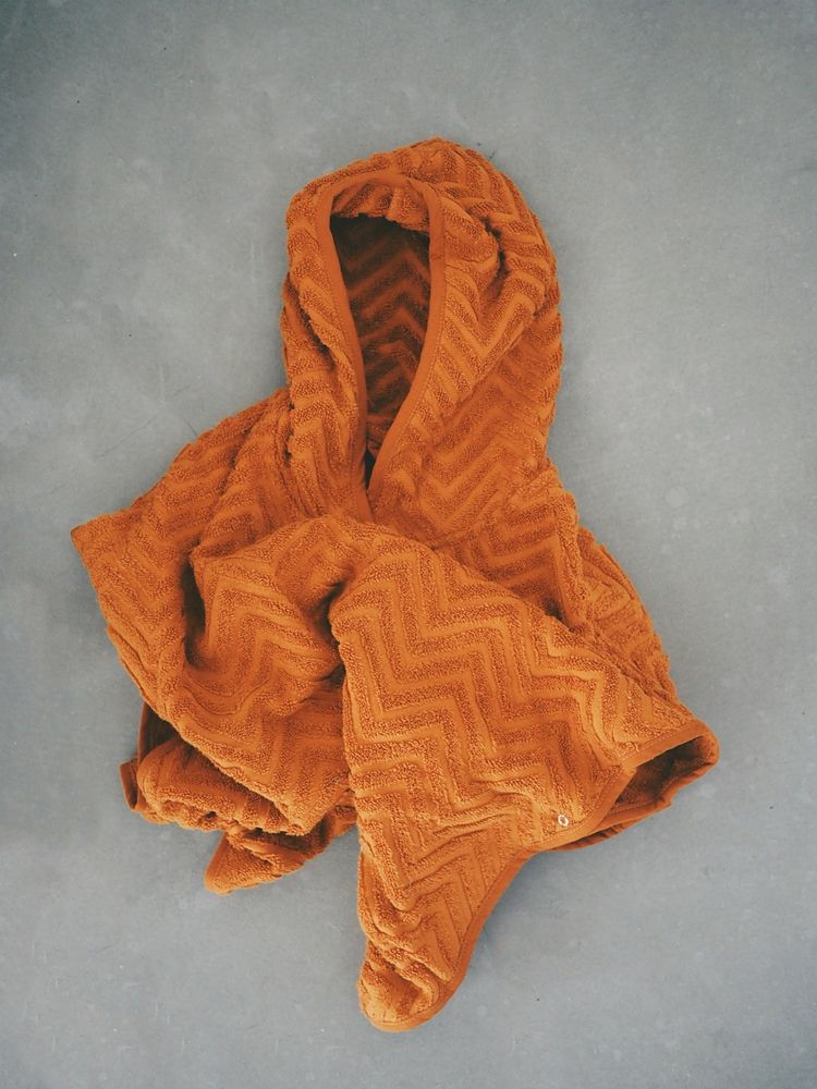 Pomarańczowe kąpielowe ponczo dla dziecka z kapturem z wzorem zygzakowym. Filibabba Poncho Zigzag Rust