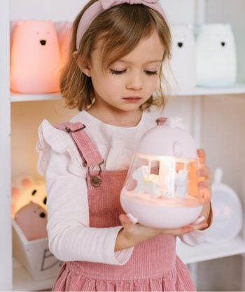Dziewczynka trzyma różową lampkę z pozytywką w kształcie kurczaczka dla dziecka. Rabbit&Friends Kurczaczek Lampka z Pozytywką Różowa