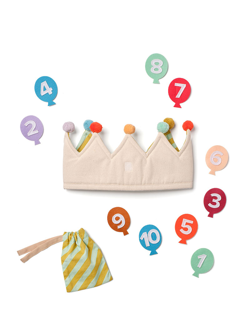 Urodzinowa korona z tkaniny kremowa z kolorowymi pomponami i woreczkiem w paski dla dziecka. Kid’s Concept urodzinowa korona