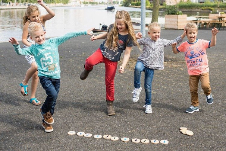 Dzieci bawiące się na zewnątrz gra naśladowania ruchu memory z drewnianymi elementami na chodniku. BS Toys Gra Naśladuj Ruch