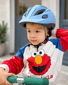 Dziecięcy kask rowerowy w kolorze niebieskim na głowie chłopca w bluzie z postacią z kreskówki. Bobike KASK dla dzieci S 52-56cm Citadel Blue