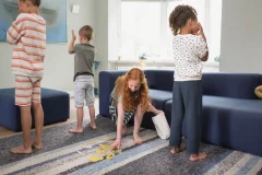 Cztery dzieci w różnym wieku ćwiczące pamięć w pokoju dziennym na dywanie