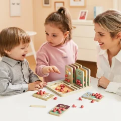 Dzieci bawiące się edukacyjną grą logiczną z dorosłą kobietą przy stole w jasnym pokoju
