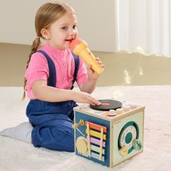 Dziecko bawiące się muzyczną kostką z instrumentami dla malucha 18m+ siedzi na podłodze z mikrofonem w ręku. Topbright Muzyczna kostka dla malucha 18m+
