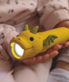 Żółta latarka w kształcie smoka trzymana przez dziecko w różowym ubraniu. Rabbit&Friends Latarka Smok DRACO