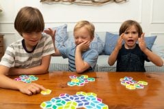 Dzieci grające w kolorową grę strategiczną z heksagonalnymi płytkami na drewnianym stole. Mobi Games Płytki Stello Gra Strategiczna