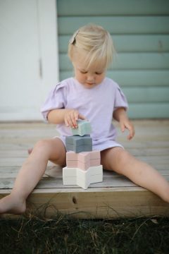 Dziecko układa pastelową wieżę z klocków w kształcie gwiazdek do zabawy dla niemowląt i małych dzieci. Mushie Wieża do Układania Gwiazdki Nesting Star Orginal