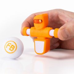 Pomarańczowy piłkarzyk Foosbot do gry zręcznościowej dla jednego gracza z białą piłeczką. Fat Brain Toy Co. Pomarańczowy Piłkarzyki Foosbots Zestaw dla Jednego Gracza