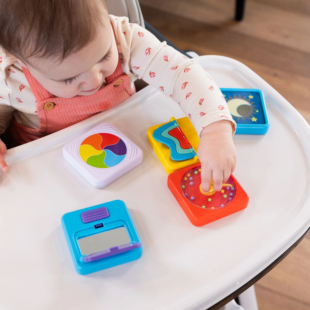 Dziecko bawi się kolorowymi sensorycznymi kwadratami z lusterkiem na białym stoliku. Fat Brain Toy Co. PlayTab Sensoryczny Kwadrat Lusterko