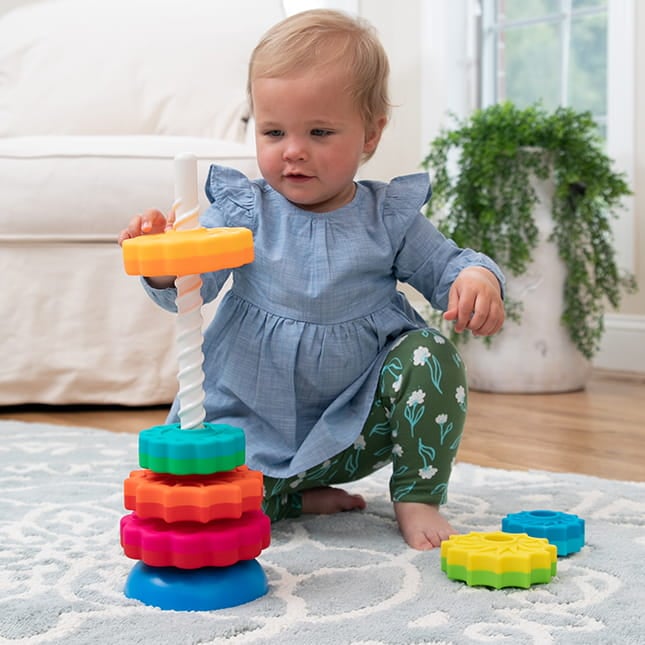 Dziecko układa kolorowe klocki 3d na zakręconej wieży do zabawy dla niemowląt. Fat Brain Toy Co. Zakręcona Wieża SpinAgain