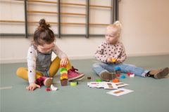 Dwoje dzieci bawi się grą zręcznościową z kolorowymi elementami lodów i kartami na podłodze. BS Toys Gra zręcznościowa Lody