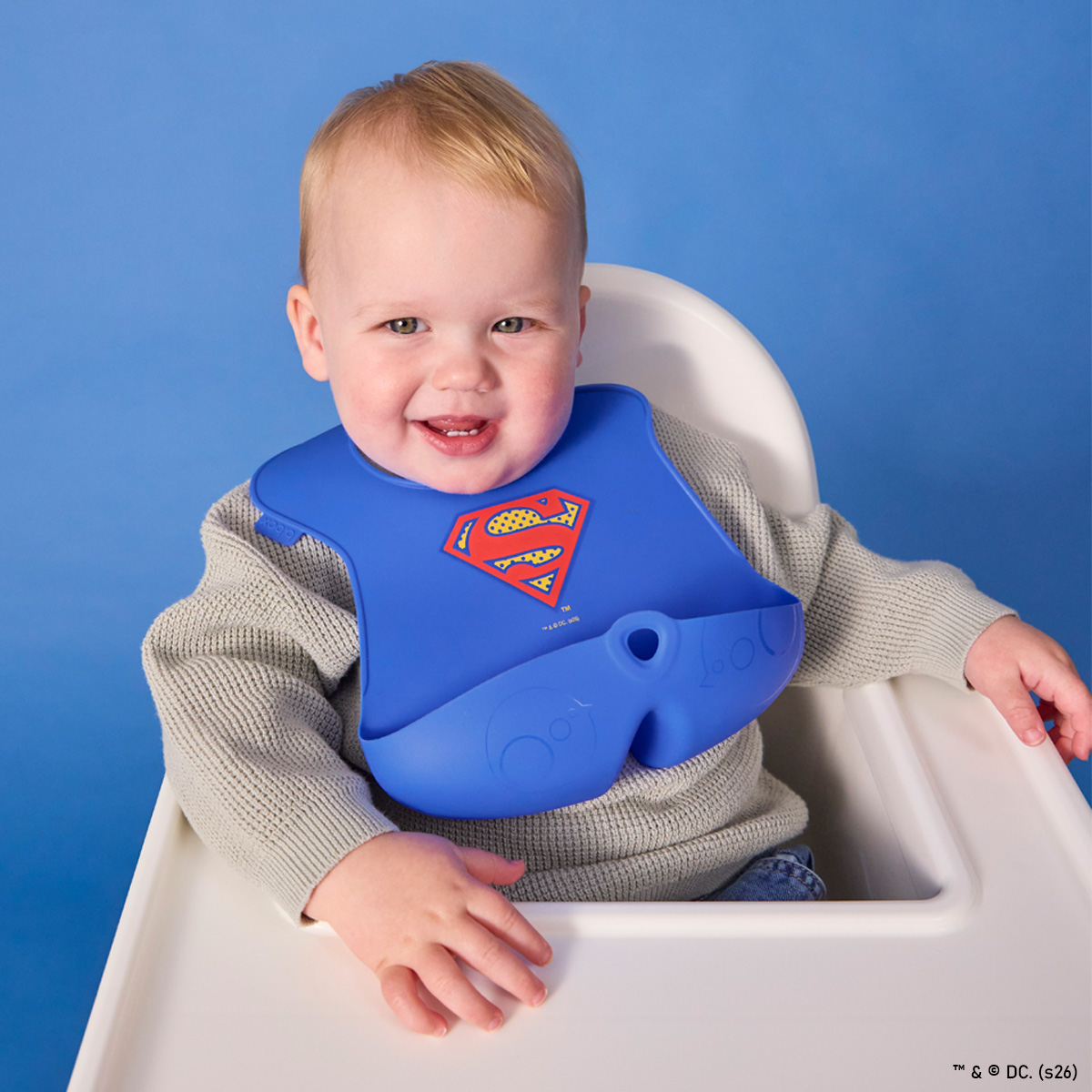 Niebieski silikonowy śliniak dla dziecka z motywem supermana z otwartą kieszonką. b.box Superman by Śliniak z otwartą kieszonką