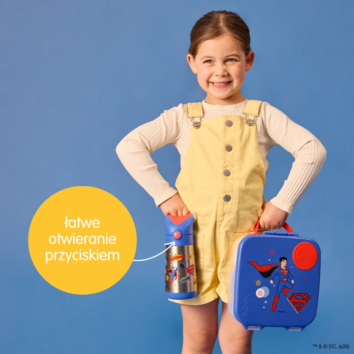 Dziecko trzyma bidon termiczny 350ml z motywem Supermana i niebieską lunchbox dla dziecka na niebieskim tle. b.box Superman by Bidon termiczny 350ml