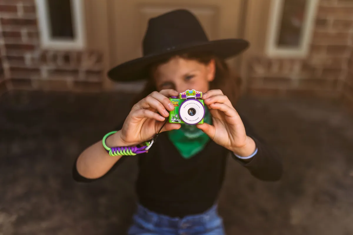 Dziecięcy aparat fotograficzny w kolorze zielonym z motywem Toy Story trzymany przez chłopca w kapeluszu i zielonym szaliku. Kiimento Aparat Mini dla Dzieci Buzz Astral z Toy Story