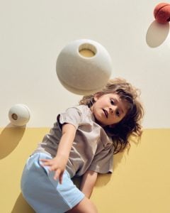 Piłka piankowa w kolorze piaskowym i żółtym dla dziecka na tle żółtej ściany. MODU Foam Ball piłka piankowa sand grey / honey yellow