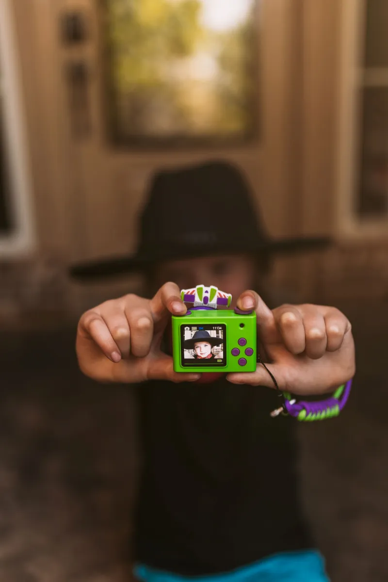 Zielony mini aparat fotograficzny dla dzieci z motywem postaci Buzz Astral z Toy Story trzymany przez dziecko. Kiimento Aparat Mini dla Dzieci Buzz Astral z Toy Story