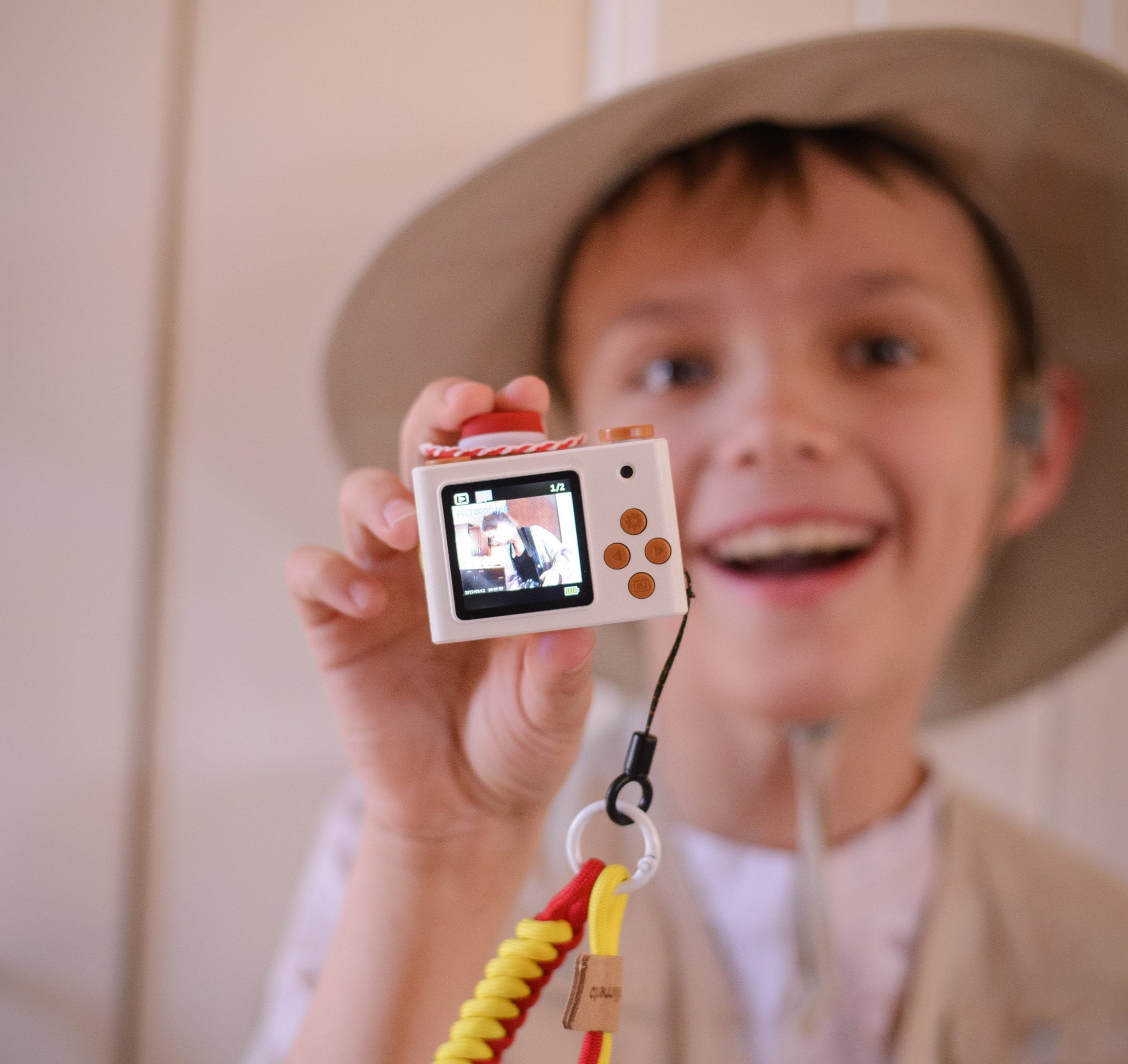 Mały aparat fotograficzny dla dzieci w kolorze białym z motywem kowbojki Jessie z Toy Story trzymany przez chłopca w kapeluszu. Kiimento Aparat Mini dla Dzieci Kowbojka Jessie z Toy Story