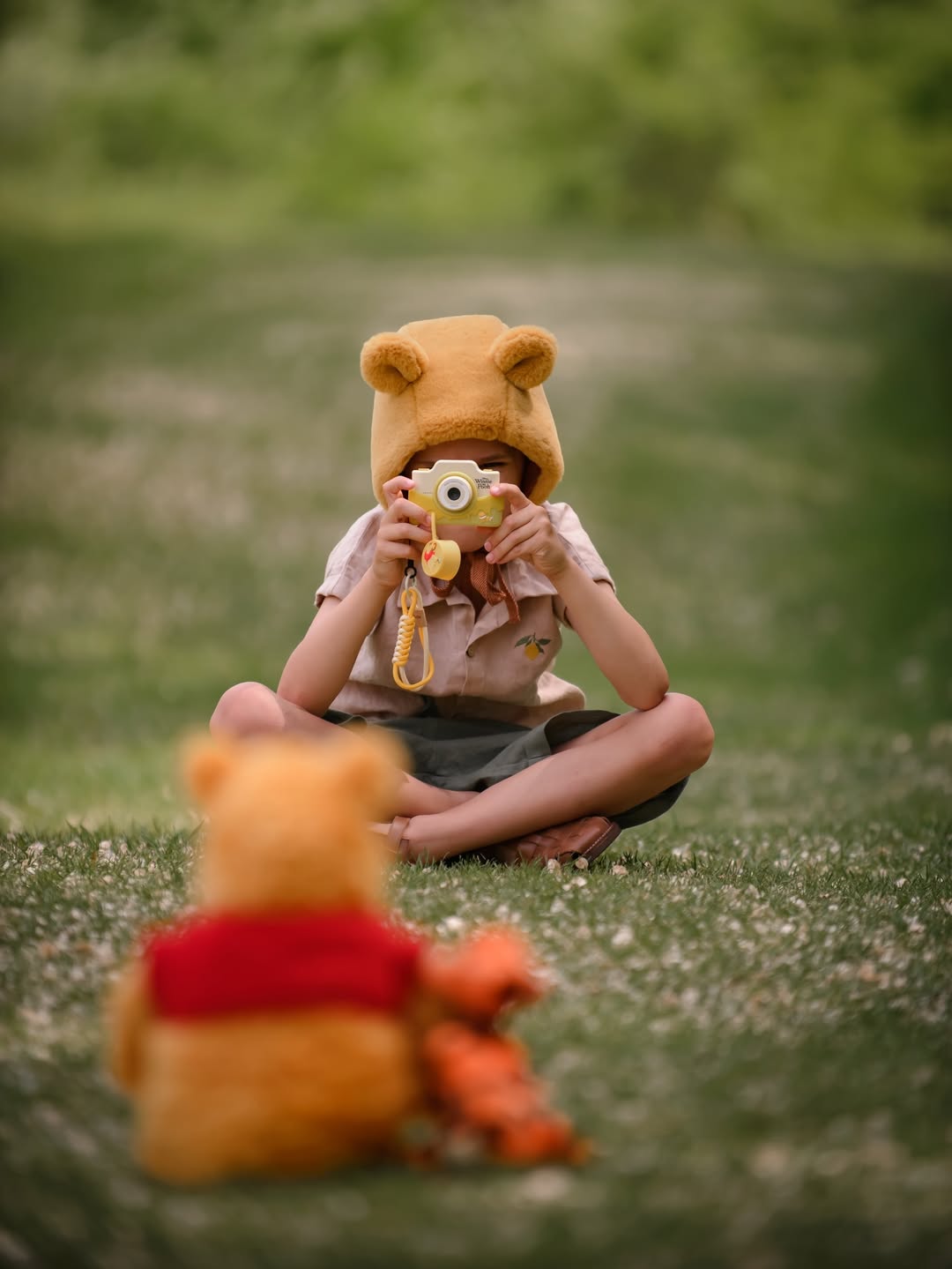 Dziecko siedzące na trawie z aparatem fotograficznym w kształcie postaci z kreskówki dla dzieci. Kiimento Aparat dla Dzieci z Dotykowym Ekranem Kubuś Puchatek Disney