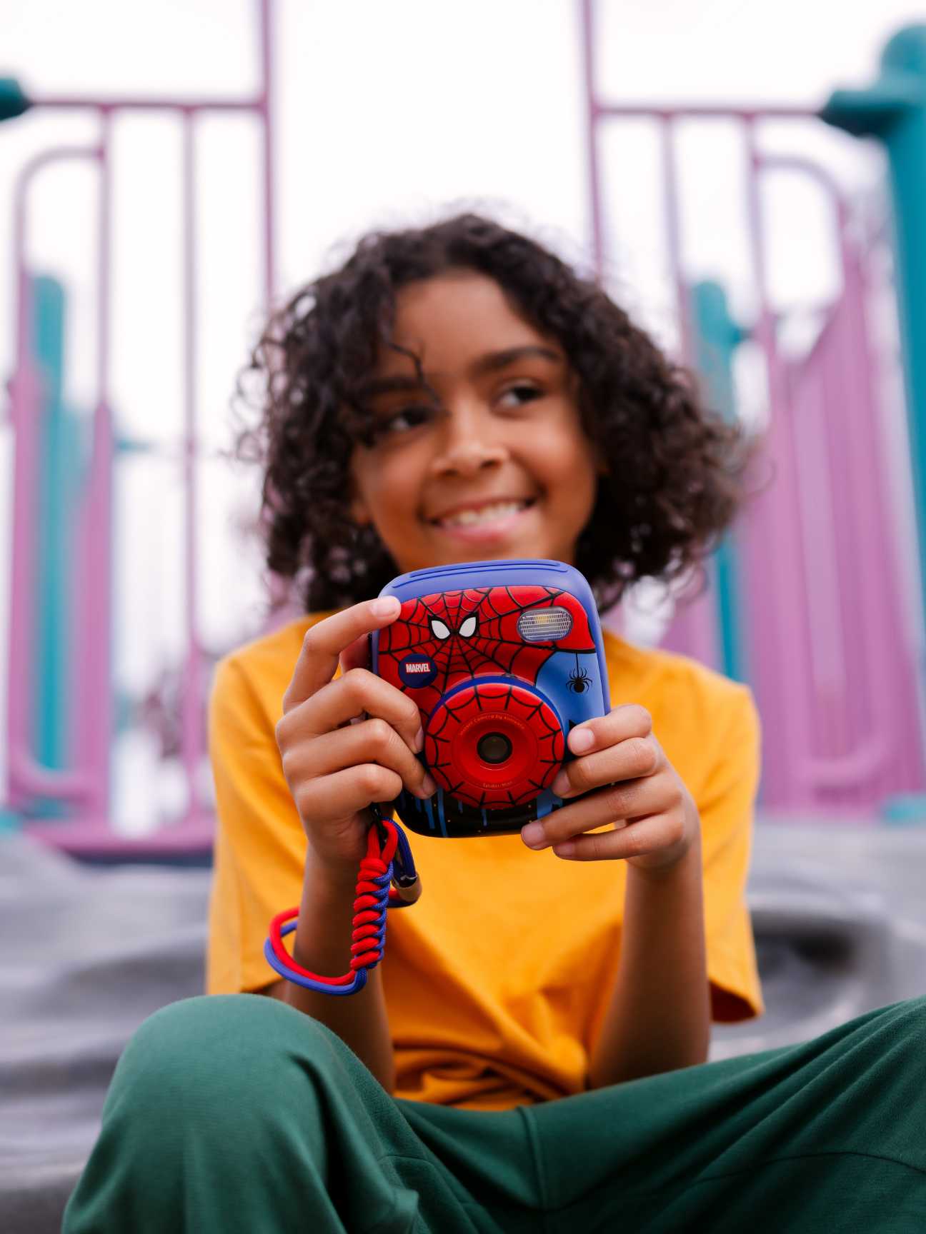 Aparat natychmiastowy z motywem Spider-Man Marvel czerwono-niebieski trzymany przez dziecko na placu zabaw. Kiimento Aparat Natychmiastowy Print Pro z Drukarką Spider-Man Marvel