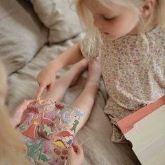 Dziecko trzymające kolorowe naklejki wielokrotnego użytku z motywem dinozaurów. Mushie Naklejki wielokrotnego użytku Dinozaury