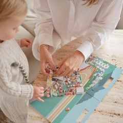 Dziecko i dorosły bawiący się naklejkami wielokrotnego użytku z motywem aut wyścigowych na papierowej planszy. Mushie Naklejki wielokrotnego użytku Auta Wyścigowe