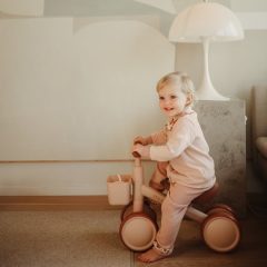 Dziecko na różowym rowerku biegowym dla niemowląt i małych dzieci w jasnym pokoju. Mushie Rowerek biegowy dla dzieci od 1 roku życia Blush