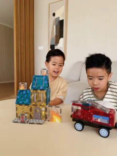 Dzieci bawiące się klockami magnetycznymi w kształcie budynków i pojazdu strażackiego czerwonego dla dzieci. CLEVERCLIXX klocki magnetyczne Fire Rescue Pack Intense 39el