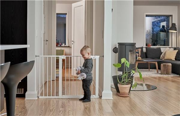 Biała metalowa bramka ochronna rozporowa w przejściu z dzieckiem w domu. Baby Dan Bramka ochronna PREMIER od 119.3 cm – 125.6 cm