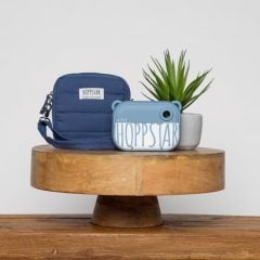 Niebieski aparat dla dzieci z torbą na ramię i doniczką w tle. Hoppstar Artist Navy Zestaw aparat dla dzieci i torba na aparat