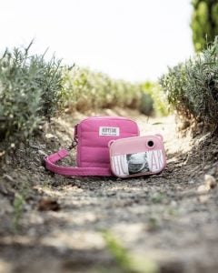 Różowy aparat dla dzieci z torbą na aparat i paskiem na ramię na ścieżce wśród roślin. Hoppstar Artist Blush Zestaw aparat dla dzieci i torba na aparat