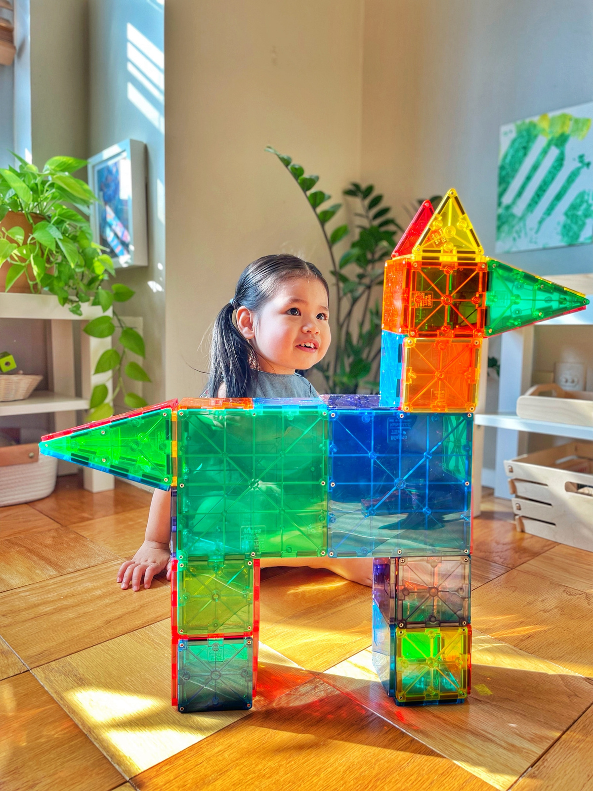 Kolorowe magnetyczne klocki konstrukcyjne zbudowane w kształt zwierzęcia z dzieckiem w tle. Magna-Tiles Klocki Magnetyczne Classic 100el