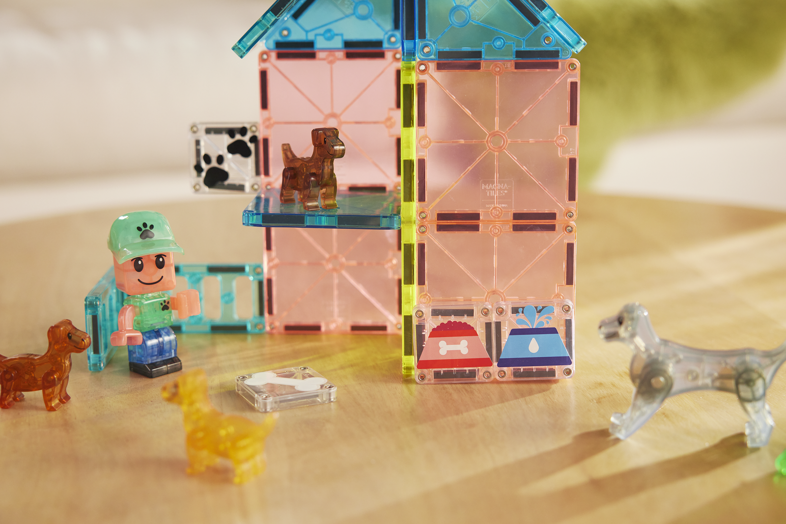 Klocki magnetyczne zbudowane w kształt domu z figurką psa, ludzikiem i zwierzątkami dla dziecka. Magna-Tiles Klocki Magnetyczne Puppy Park 27el