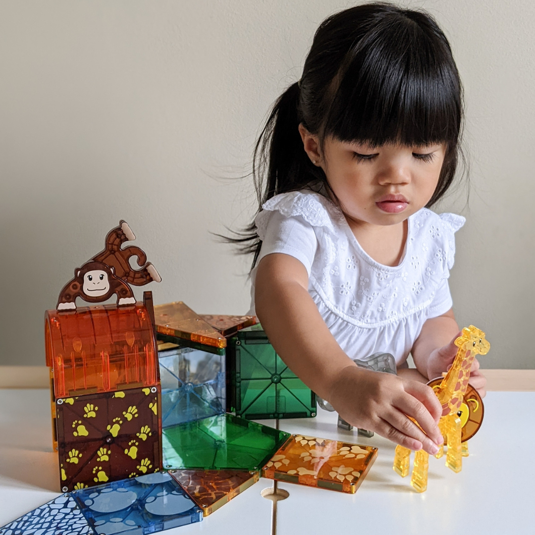 Dziecko bawi się magnetycznymi klockami safari z figurkami zwierząt w kolorach pomarańczowym zielonym i niebieskim. Magna-Tiles Klocki Magnetyczne Safari Animals 25el