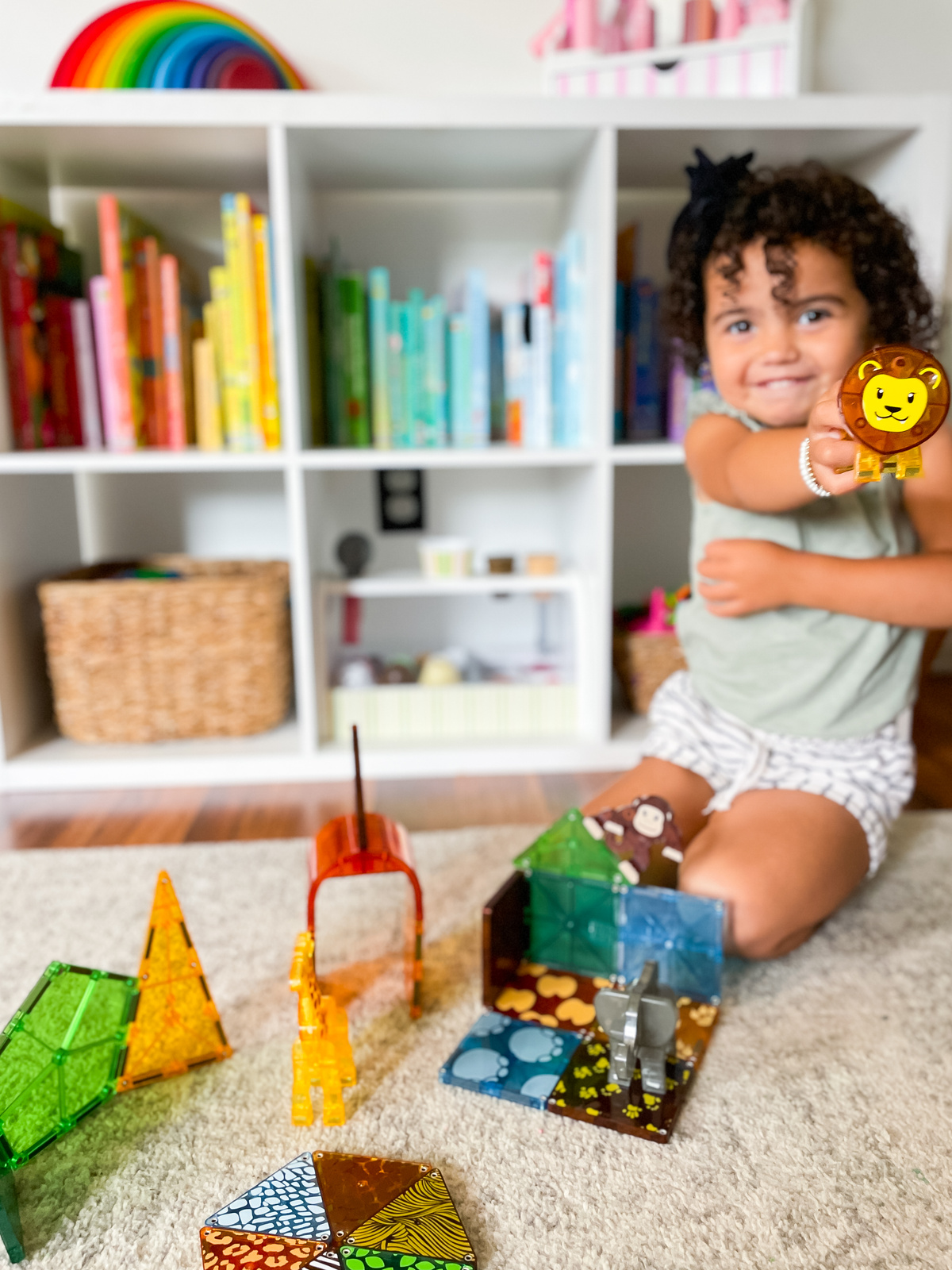 Dziecko bawi się kolorowymi klockami magnetycznymi safari z figurkami zwierząt na dywanie. Magna-Tiles Klocki Magnetyczne Safari Animals 25el
