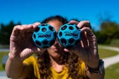 Dwie niebieskie gumowe piłeczki Moon Ball trzymane w dłoniach. Waboba Piłeczka Moon Ball niebieska