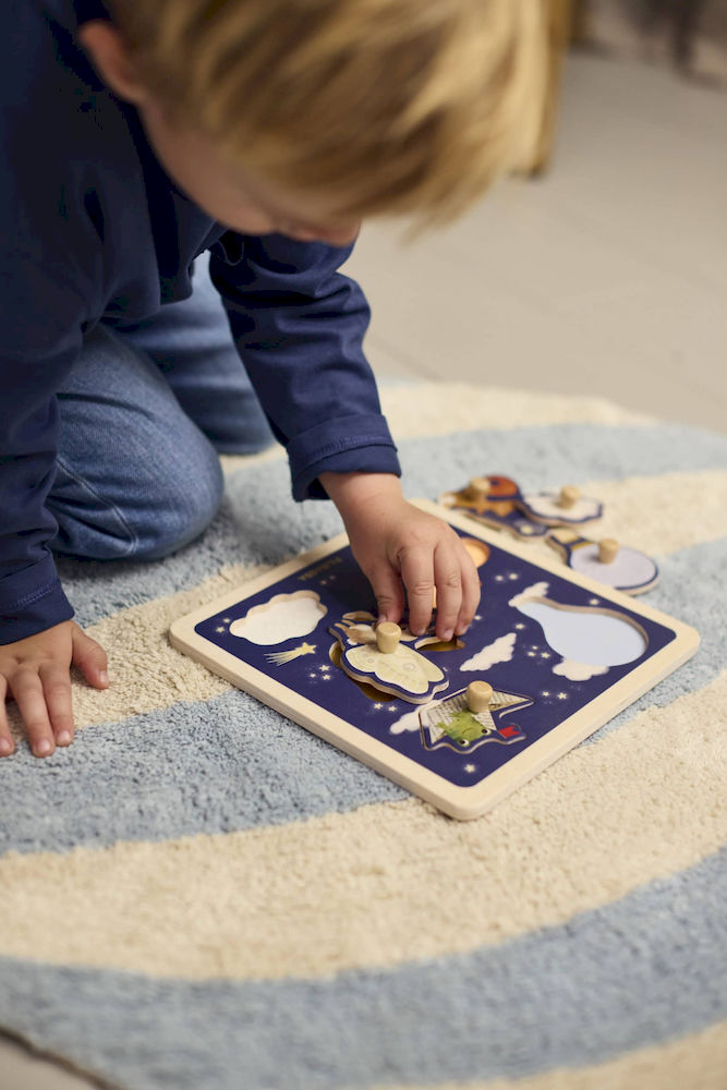 Dziecko układa drewniane puzzle sensoryczne z motywem zwierząt na niebieskiej planszy. Filibabba Drewniane puzzle sensoryczne Little Adventurers