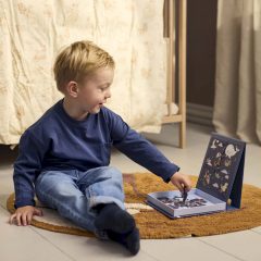 Chłopiec układa magnetyczne puzzle z motywem przygodowym przy otwartej książeczce z obrazkami. Filibabba Puzzle magnetyczne Dreamy Adventurers