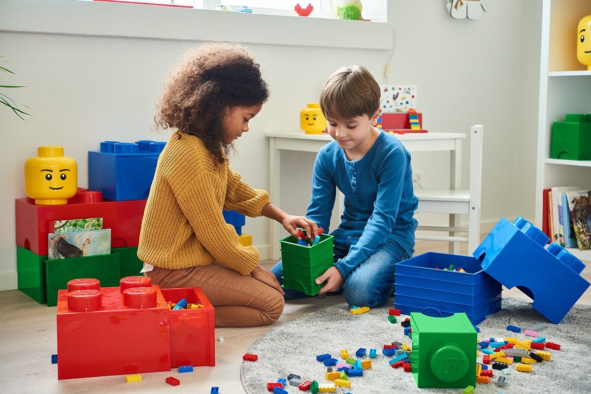 Czerwony pojemnik na klocki w kształcie klocka z wysuwaną szufladą zawierającą kolorowe klocki lego