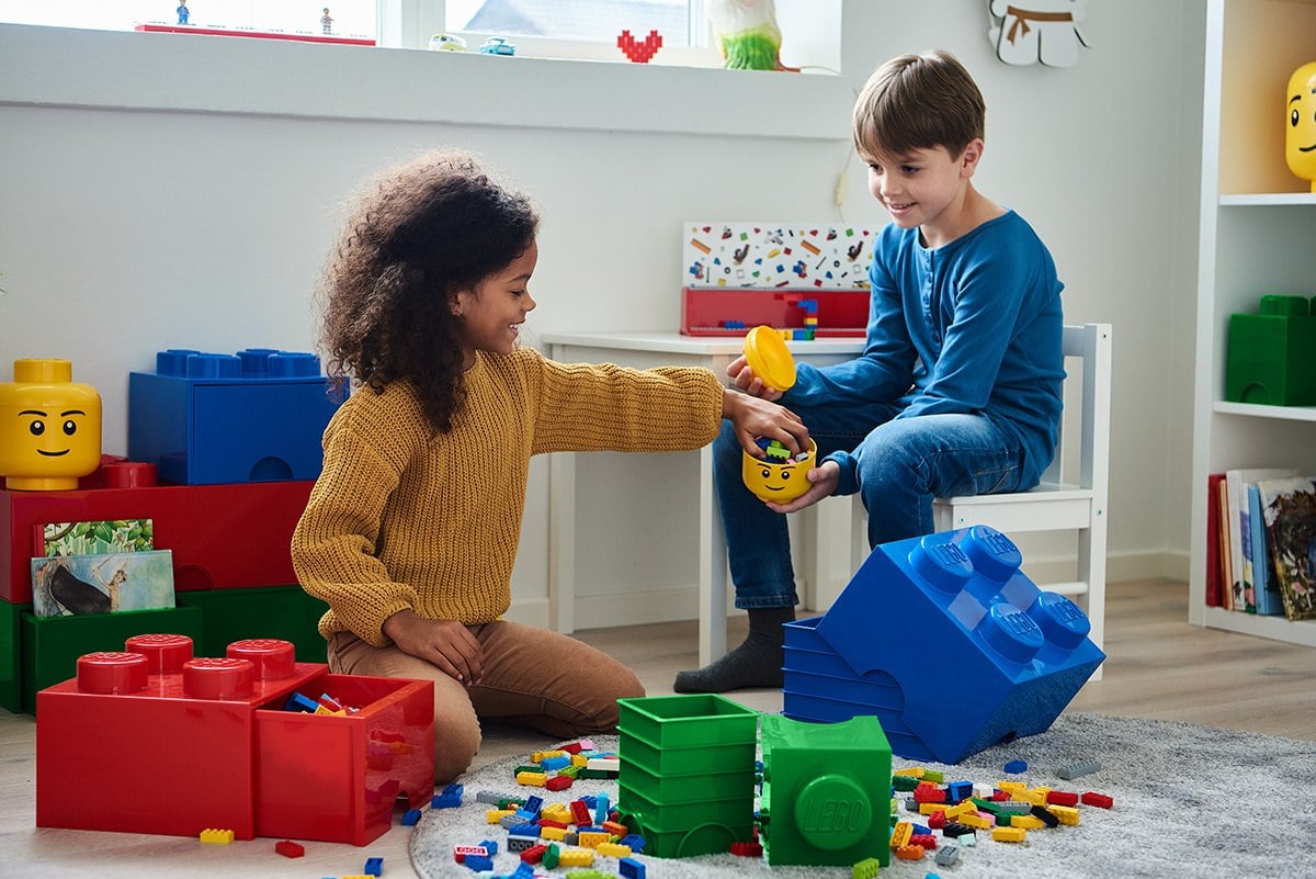 Czerwony pojemnik w kształcie klocka z wysuniętą szufladą, zawierającą kolorowe klocki lego
