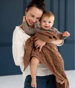 Cynamonowy dzianinowy kocyk z wełny merino dla dziecka trzymanego przez mamę