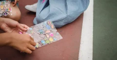Dziecko wybiera kolorowe naklejki transferowe z arkusza podczas zabawy plastycznej