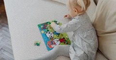 Dziecko układa kolorowe puzzle z obrazkiem zwierząt na łóżku